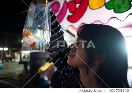 一個女人在夜間節日里看著金魚 一個女人在夜間節日里看著金魚 106753360