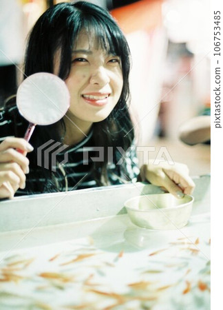 A girl playing with scooping goldfish at the fair 106753485