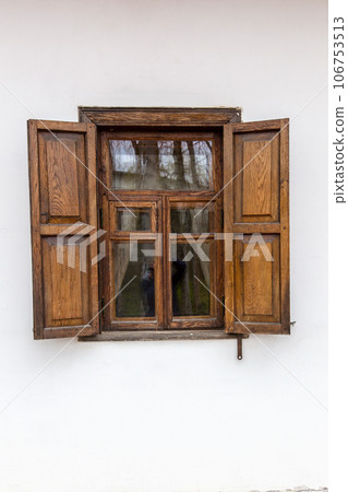 Window with wooden shutter in an old vintage house. Open front brown shutter window on white wall. 106753513