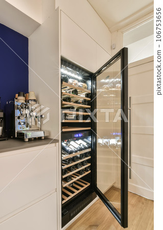 a wine cooler in a kitchen with wood flooring and blue walls behind the fridge is an open door that opens to reveal a a wine cooler in a kitchen with wood flooring and blue walls behind the fridge is an open door that opens to reveal a 106753656