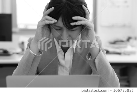 Monochrome image of a female office worker holding her head and worrying 106753855