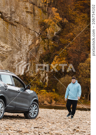 man at the rocky beach in mountain river near car man at the rocky beach in mountain river near car 106754102
