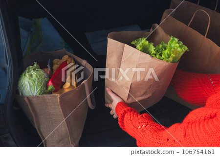 woman hand put bags with groceries shopping into cur trunk woman hand put bags with groceries shopping into cur trunk 106754161