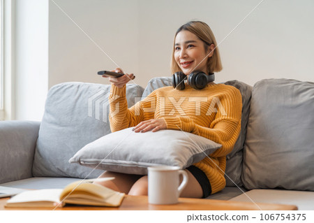 Asian young beautiful woman watch fun movie on television at home. woman casual girl feel happy and relax sit on sofa 106754375