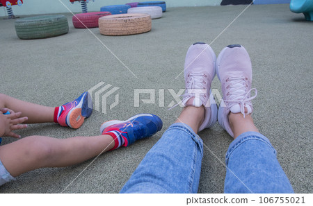 legs on woman and her child sitting on the ground on the playground.top view . legs on woman and her child sitting on the ground on the playground.top view . 106755021