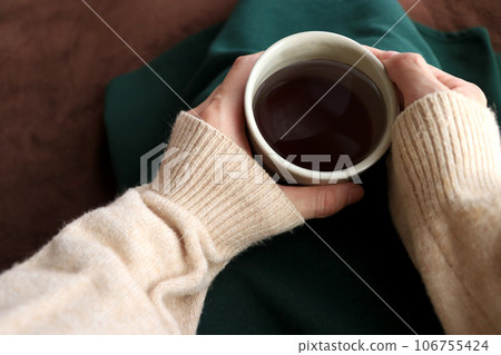 Woman's hand holding a mug containing hot coffee Woman's hand holding a mug containing hot coffee 106755424