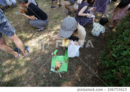 蹲下來吃在節日攤上買的午餐。 蹲下來吃在節日攤上買的午餐。 106755623