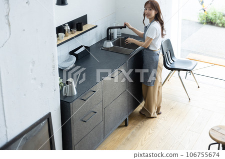 A woman wearing an apron standing in the kitchen A woman wearing an apron standing in the kitchen 106755674