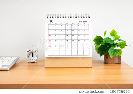 The October 2023, Monthly desk calendar for 2023 year on wooden table with alarm clock. 106756953