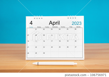The April monthly desk calendar for 2024 year and pen on wooden table with blue color background. 106756971