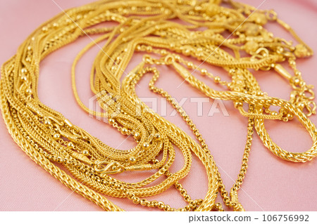 The Many gold necklaces on pink color cloth background. The Many gold necklaces on pink color cloth background. 106756992