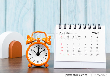 A December 2023 Monthly desk calendar for the organizer to plan 2023 year with alarm clock on wooden table. 106757026