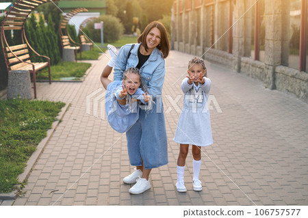 The mother shakes her daughter showing four fingers and laughing merrily. Mom and kids have a good weekend in the summer, walking around the city together 106757577