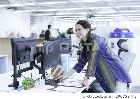 Senior business woman reaching for laptop 106758472