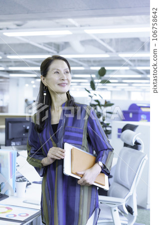 站在辦公室的一位高級女商人的肖像，垂直位置 106758642