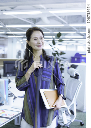 Portrait of a senior business woman standing in the office, vertical position Portrait of a senior business woman standing in the office, vertical position 106758654