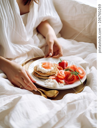 Beautiful woman having breakfast in bed, home bedroom interior with bright morning light, healthy food on cozy decorated tray, weekend meal Beautiful woman having breakfast in bed, home bedroom interior with bright morning light, healthy food on cozy decorated tray, weekend meal 106760269