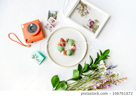 Background with dessert, polaroid camera and flowers. Top view on white table 106761872
