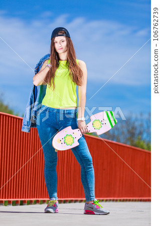 Teenage girl skater riding skateboard on street. 106762739