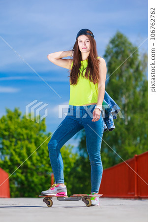 Teenage girl skater riding skateboard on street. 106762762