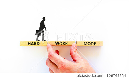 Hard work mode symbol. Concept words Hard work mode on wooden block on a beautiful white table white background. Businessman hand. Business and Hard work mode concept. Copy space. Hard work mode symbol. Concept words Hard work mode on wooden block on a beautiful white table white background. Businessman hand. Business and Hard work mode concept. Copy space. 106763234