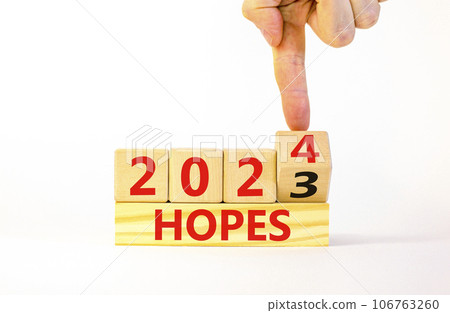 2024 hopes new year symbol. Businessman turns a wooden cube and changes words Hopes 2023 to Hopes 2024. Beautiful white background, copy space. Business 2024 hopes new year concept. 2024 hopes new year symbol. Businessman turns a wooden cube and changes words Hopes 2023 to Hopes 2024. Beautiful white background, copy space. Business 2024 hopes new year concept. 106763260