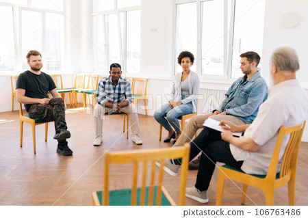 Portrait of desperate black male talk share problem with multicultural people in group psychological therapy at office. Diverse multiethnic man and women help upset patient. Concept of mental health Portrait of desperate black male talk share problem with multicultural people in group psychological therapy at office. Diverse multiethnic man and women help upset patient. Concept of mental health 106763486