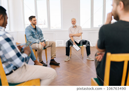 Portrait of friendly mature male mentor corporate leader communicating with multiracial business professional team, teaching interns staff group engaged in discussion at training meeting. 106763490