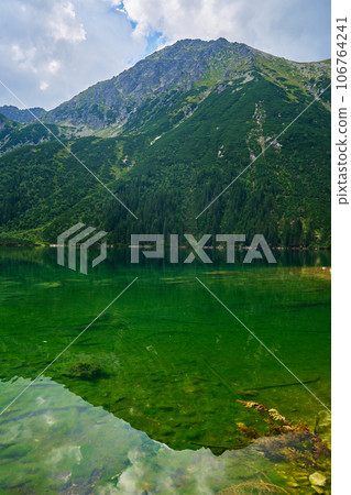 Amazing view on mountains range near beautiful lake at summer day. Tatra National Park in Poland. Panoramic view on Morskie Oko or Sea Eye lake in Five lakes valley 106764241