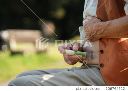Diabetic senior patient injecting insulin in belly outdoors. 106764312
