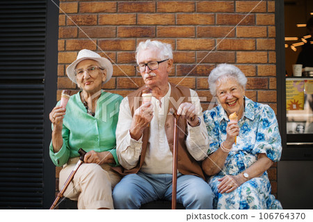 Portrait of three senior friends in the city, eating ice cream on a hot summer day. 106764370