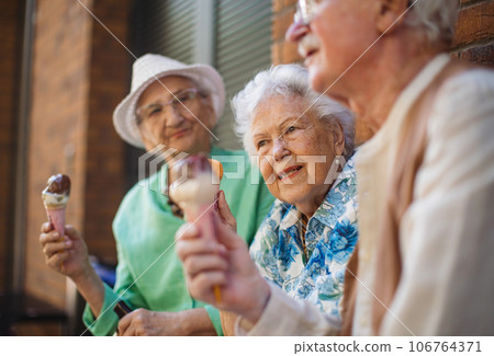 Portrait of three senior friends in the city, eating ice cream on a hot summer day. 106764371