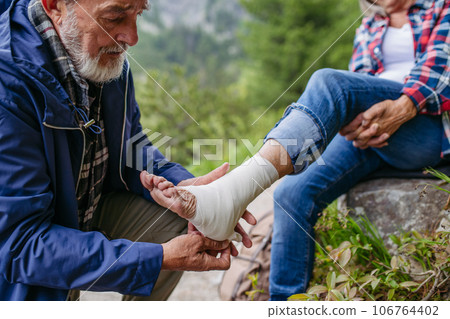 Senior woman injured her ankle during hike in the mountains. 106764402