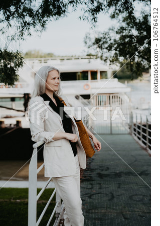 Portrait of beautiful female manager in middle age with gray hair walking through the city. Portrait of beautiful female manager in middle age with gray hair walking through the city. 106764512
