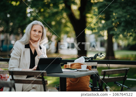 Portrait of beautiful female manager in middle age with gray hair working outdoors. 106764522