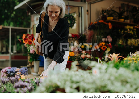 Portrait of a beautiful mature woman shopping at fresh flowers market in the city. Portrait of a beautiful mature woman shopping at fresh flowers market in the city. 106764532