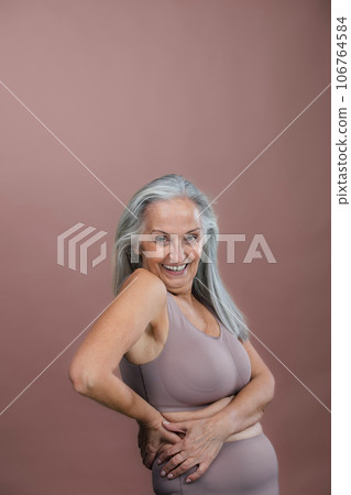 Portrait of senior woman in lingerie, studio shoot. 106764584