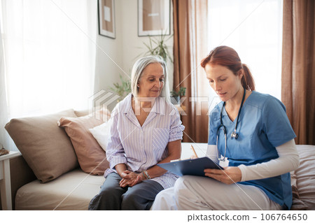Female caregiver doing regular check-up of senior woman in her home. 106764650