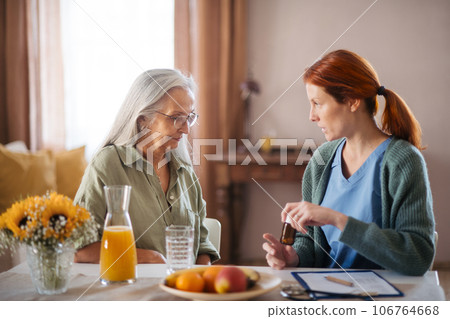 Nurse explaining senior woman how to take medicine. 106764668