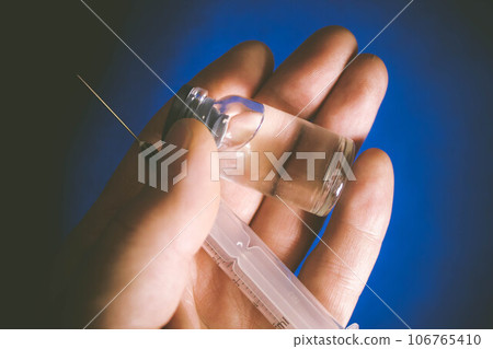 Vaccine in vitro. Medicine in a flask on a blue background. Vaccine in vitro. Medicine in a flask on a blue background. 106765410