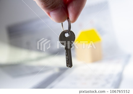 Keys in hand and house. Handing over the keys to the apartment. 106765552