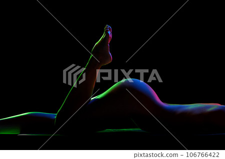 Cropped image of naked female body against black studio background in neon lights. Buttocks Cropped image of naked female body against black studio background in neon lights. Buttocks 106766422