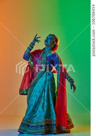 Elegant, mature, beautiful indian woman in traditional clothes, dress posing against gradient studio background in neon light Elegant, mature, beautiful indian woman in traditional clothes, dress posing against gradient studio background in neon light 106766454