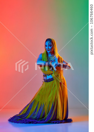 Odissi dance. Beautiful young woman in traditional dress dancing against gradient studio background in neon light 106766460