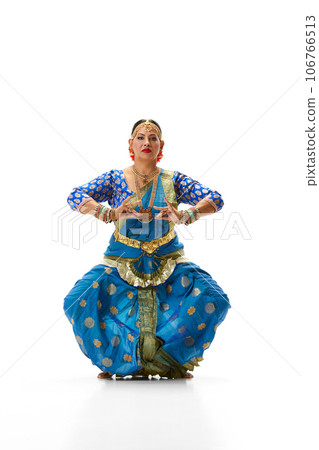 Indian beautiful woman dancing traditional dance in elegant blue dress against white studio background 106766513