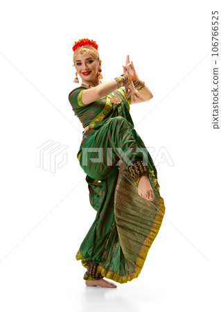 Beautiful woman in green dress dancing traditional indian dance bharatanatyam against white studio background 106766525