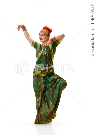 Beautiful woman in green dress dancing traditional indian dance bharatanatyam against white studio background 106766537