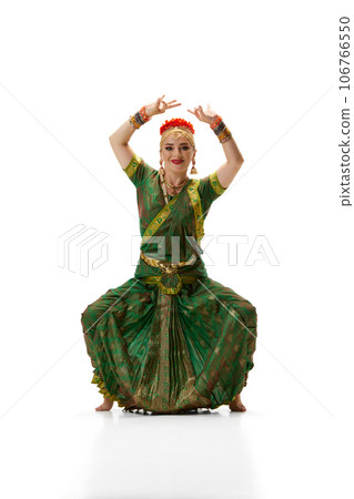 Elegance of traditional indian dance. Beautiful woman in green dress making performance against white studio background Elegance of traditional indian dance. Beautiful woman in green dress making performance against white studio background 106766550