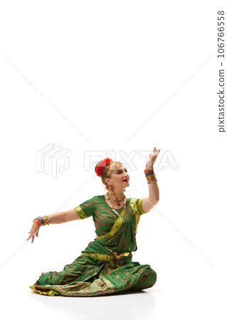Following indian traditions. Beautiful woman in green dress dancing against white studio background 106766558