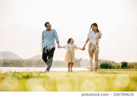 Happy family taking a walk together in the countryside on a beautiful sunny day, feeling healthy and active in the outdoors, Happy family day Happy family taking a walk together in the countryside on a beautiful sunny day, feeling healthy and active in the outdoors, Happy family day 106766626